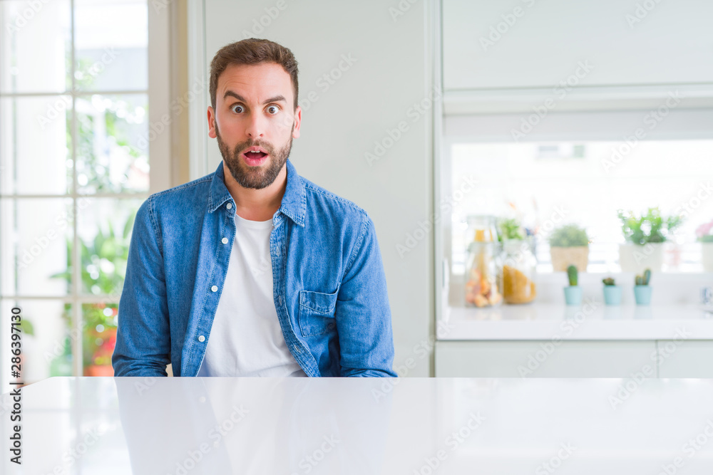 Handsome man at home afraid and shocked with surprise expression, fear and excited face. Handsome man at home afraid and shocked with surprise expression, fear and excited face.