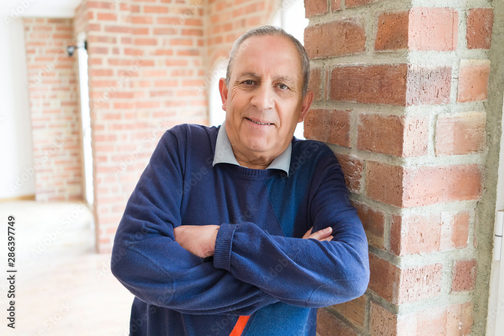 Handsome middle age senior man smiling cheerful, happy and positive with crossed arms over bricks wall background