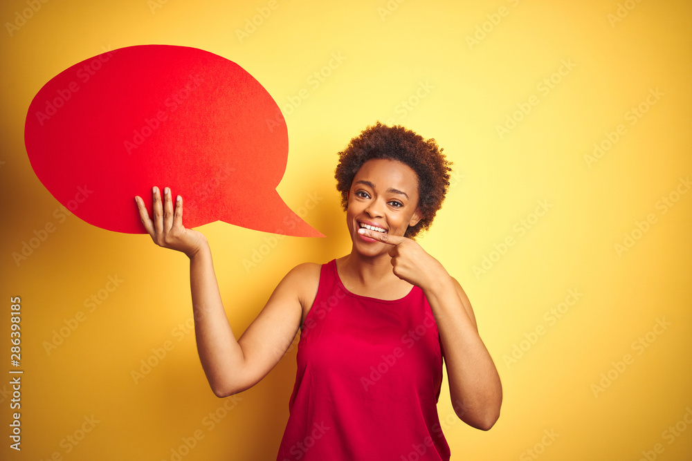 Young african american woman holding speech bubble over yellow isolated background very happy pointing with hand and finger Young african american woman holding speech bubble over yellow isolated background very happy pointing with hand and finger