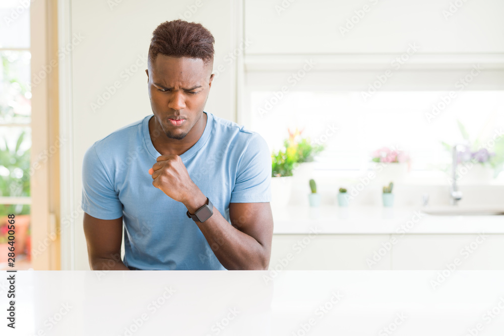 Handsome african american man wearing casual t-shirt at home feeling unwell and coughing as symptom for cold or bronchitis. Healthcare concept. Handsome african american man wearing casual t-shirt at home feeling unwell and coughing as symptom for cold or bronchitis. Healthcare concept.