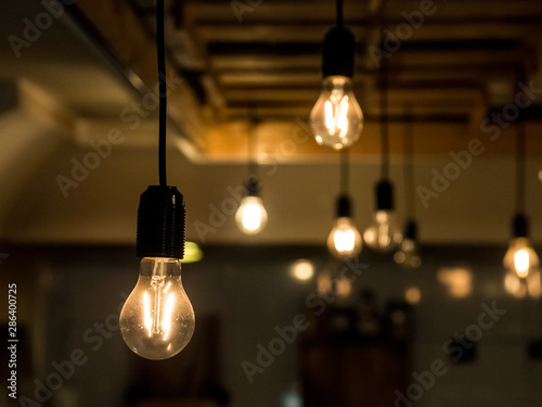 Vintage incandescence lightbulbs, with their iconic filament, hanging on the roof inside a hipsterish industrial room
