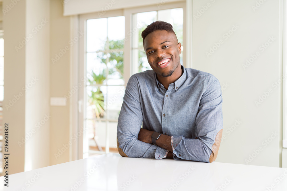 Handsome african american man on white table happy face smiling with crossed arms looking at the camera. Positive person.