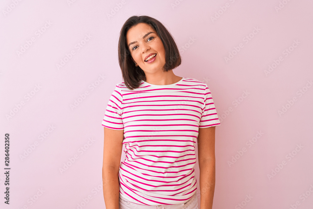 Young beautiful woman wearing striped t-shirt standing over isolated pink background looking away to side with smile on face, natural expression. Laughing confident. Young beautiful woman wearing striped t-shirt standing over isolated pink background looking away to side with smile on face, natural expression. Laughing confident.