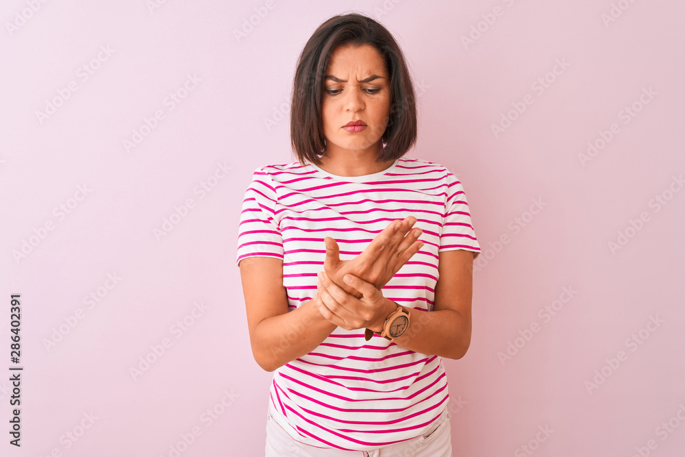 Young beautiful woman wearing striped t-shirt standing over isolated pink background Suffering pain on hands and fingers, arthritis inflammation Young beautiful woman wearing striped t-shirt standing over isolated pink background Suffering pain on hands and fingers, arthritis inflammation