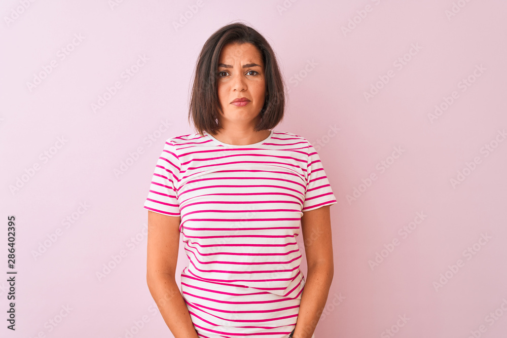 Young beautiful woman wearing striped t-shirt standing over isolated pink background depressed and worry for distress, crying angry and afraid. Sad expression.