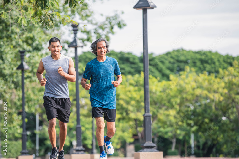 Obraz premium Young man and elderly man running in the city. Healthy lifestyle concept. Young fitness man and elderly man runner athlete running at park. Elderly sporty man running in morning workout.