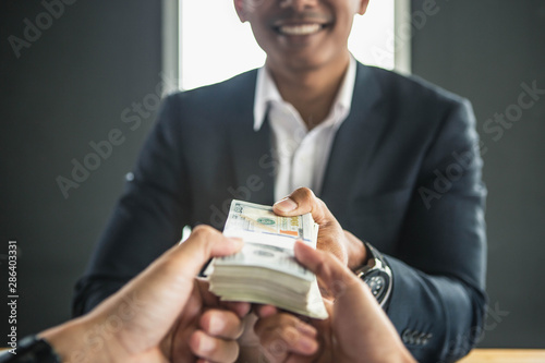 Man offering batch of hundred dollar bills. Hands close up. Venality, bribe, corruption concept. Hand giving money - United States Dollars (or USD). Hand receiving money from businessman.