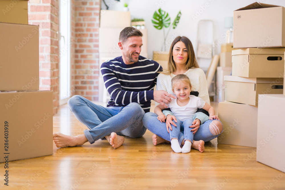 Beautiful family sitting on the floor playing with his kid at new home around cardboard boxes Beautiful family sitting on the floor playing with his kid at new home around cardboard boxes