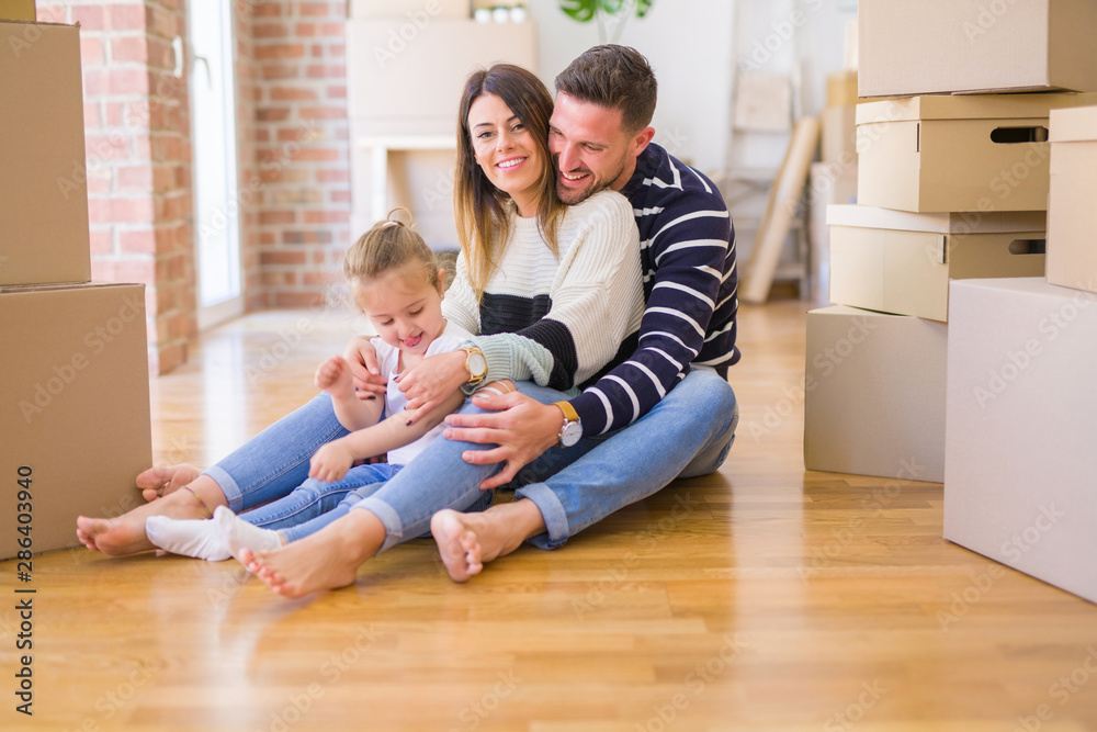 Beautiful family sitting on the floor playing with his kid at new home around cardboard boxes Beautiful family sitting on the floor playing with his kid at new home around cardboard boxes
