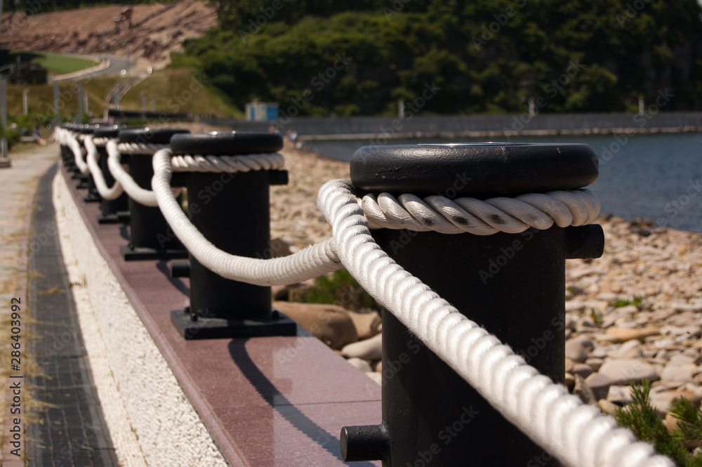 fencing from the bollards with tight rope near the pebble beach near the sea fencing from the bollards with tight rope near the pebble beach near the sea