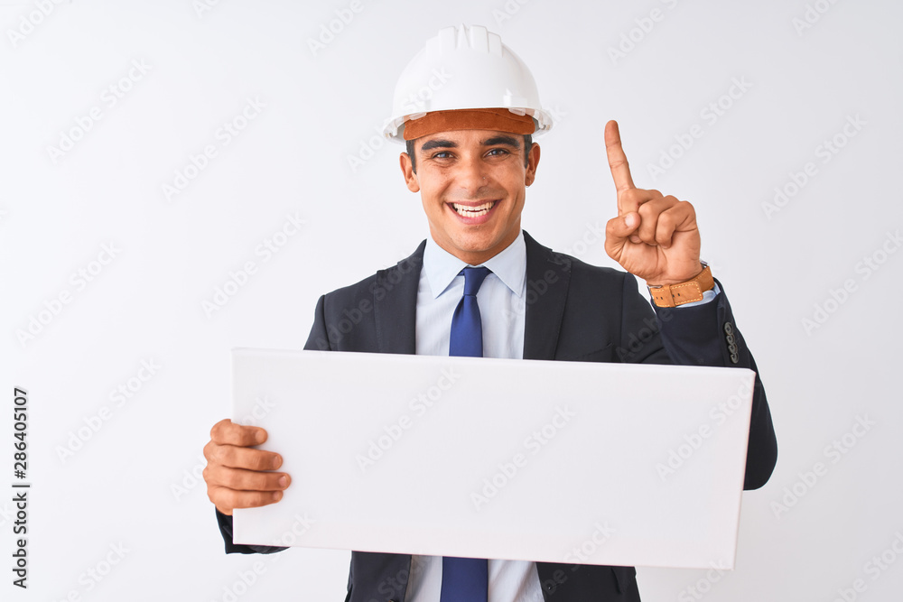 Young handsome architect man wearing helmet holding banner over isolated white background surprised with an idea or question pointing finger with happy face, number one Young handsome architect man wearing helmet holding banner over isolated white background surprised with an idea or question pointing finger with happy face, number one