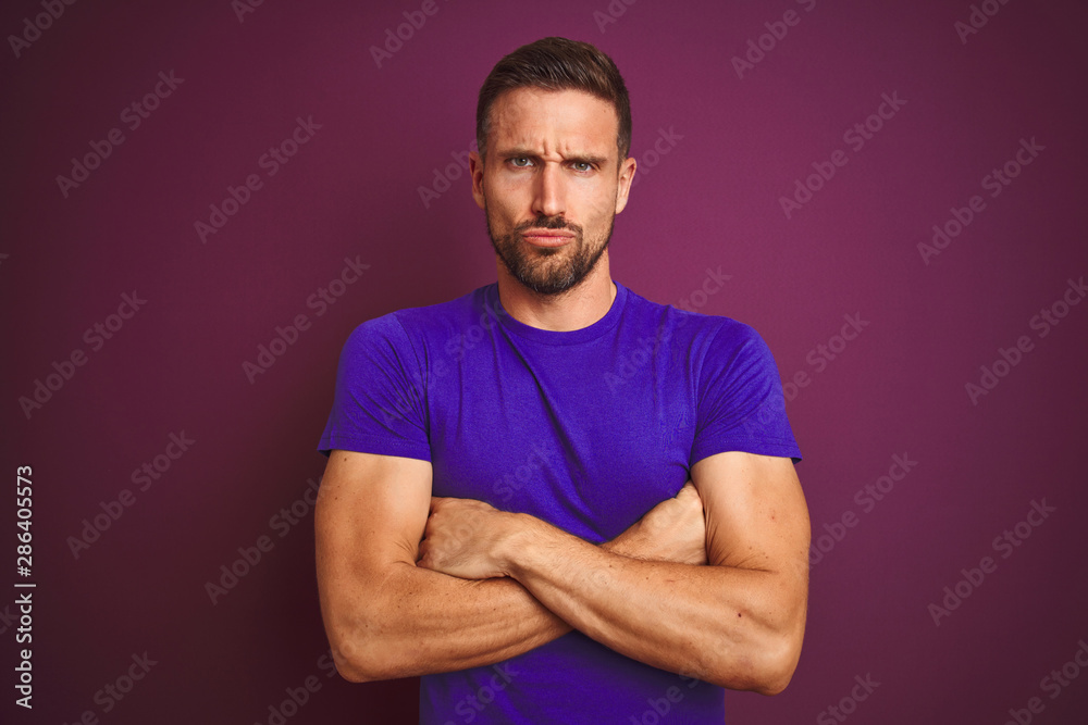 Young man wearing casual purple t-shirt over lilac isolated background skeptic and nervous, disapproving expression on face with crossed arms. Negative person. Young man wearing casual purple t-shirt over lilac isolated background skeptic and nervous, disapproving expression on face with crossed arms. Negative person.