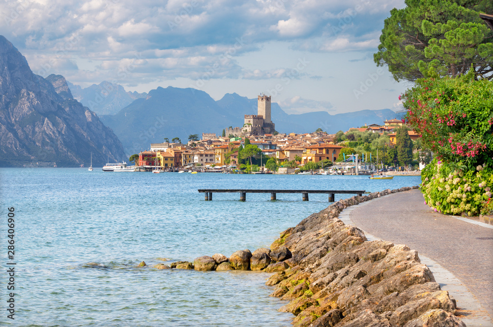 Malcesine - The promenade over the Lago di Garda lake with the town and castle in the background. - obrazy, fototapety, plakaty 