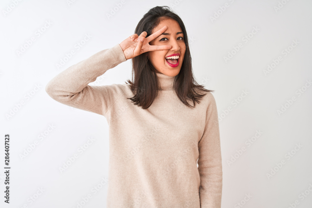 Beautiful chinese woman wearing turtleneck sweater standing over isolated white background Doing peace symbol with fingers over face, smiling cheerful showing victory Beautiful chinese woman wearing turtleneck sweater standing over isolated white background Doing peace symbol with fingers over face, smiling cheerful showing victory