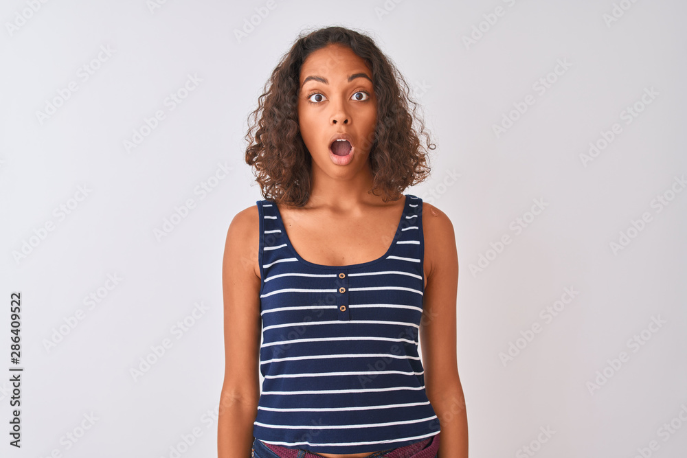 Young brazilian woman wearing striped t-shirt standing over isolated white background afraid and shocked with surprise expression, fear and excited face.