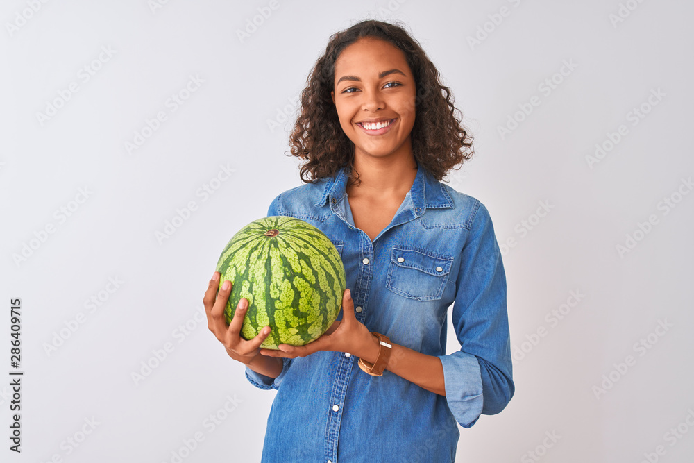 Young brazilian woman holding watermelon standing over isolated white background with a happy face standing and smiling with a confident smile showing teeth Young brazilian woman holding watermelon standing over isolated white background with a happy face standing and smiling with a confident smile showing teeth