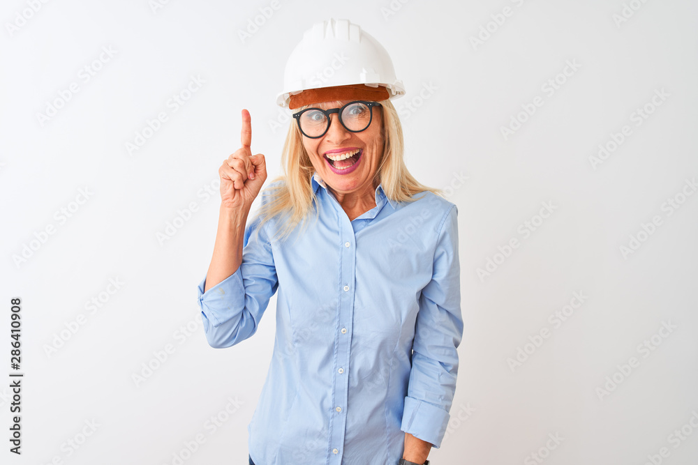Middle age architect woman wearing glasses and helmet over isolated white background pointing finger up with successful idea. Exited and happy. Number one.