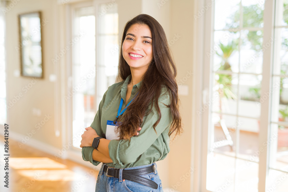 Young beautiful business woman wearing id card and smiling confident with crossed arms Young beautiful business woman wearing id card and smiling confident with crossed arms