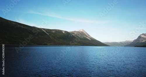 Gjevilvatnet is a beautiful lake in Norway. It is a popular tourist destination both during winter and summer. Aerial footage flying at low altitude over water towards the majestic mountains. photo