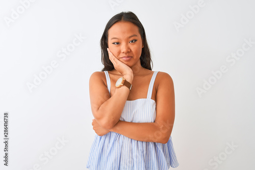 Young chinese woman wearing casual striped dress standing over isolated white background thinking looking tired and bored with depression problems with crossed arms.