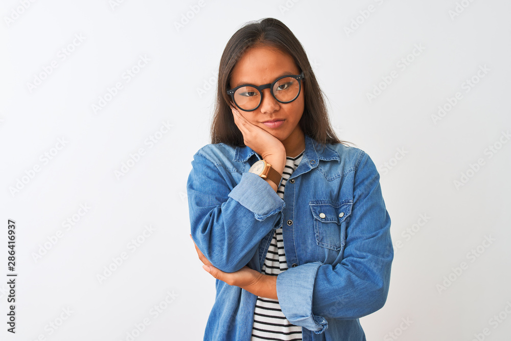 Young chinese woman wearing denim shirt and glasses over isolated white background thinking looking tired and bored with depression problems with crossed arms.