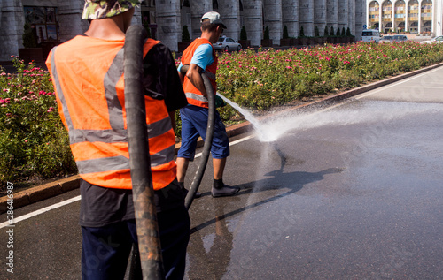 Canvas Print Employees of the municipality washes the street with water pressure from the car