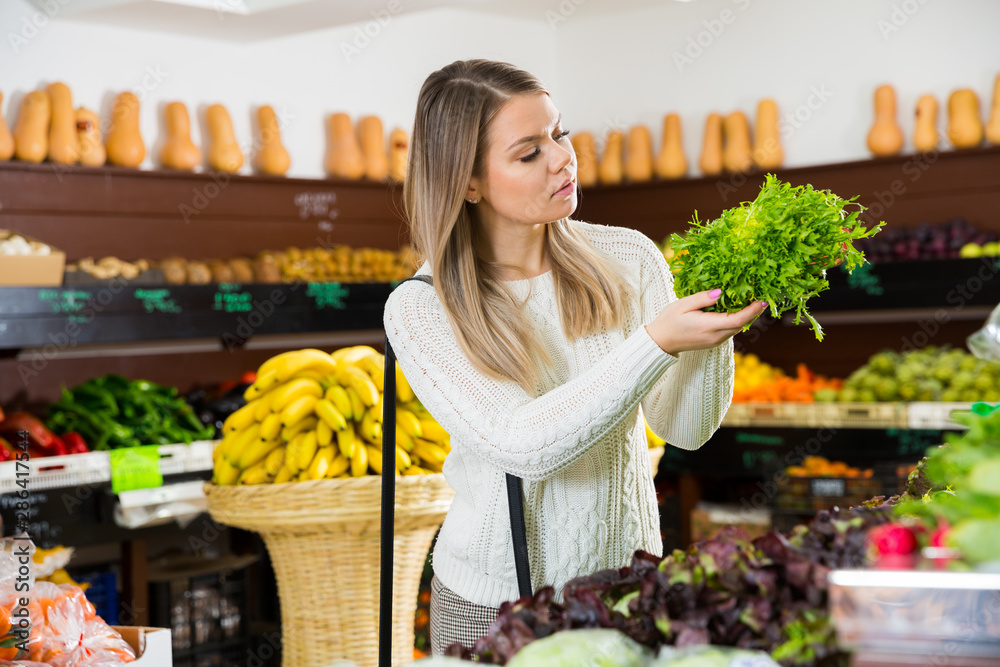 Girl choosing greens in supermarket