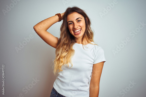 Young beautiful woman wearing casual white t-shirt over isolated background smiling confident touching hair with hand up gesture, posing attractive and fashionable
