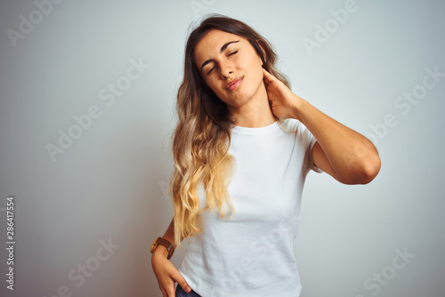 Young beautiful woman wearing casual white t-shirt over isolated background Suffering of neck ache injury, touching neck with hand, muscular pain