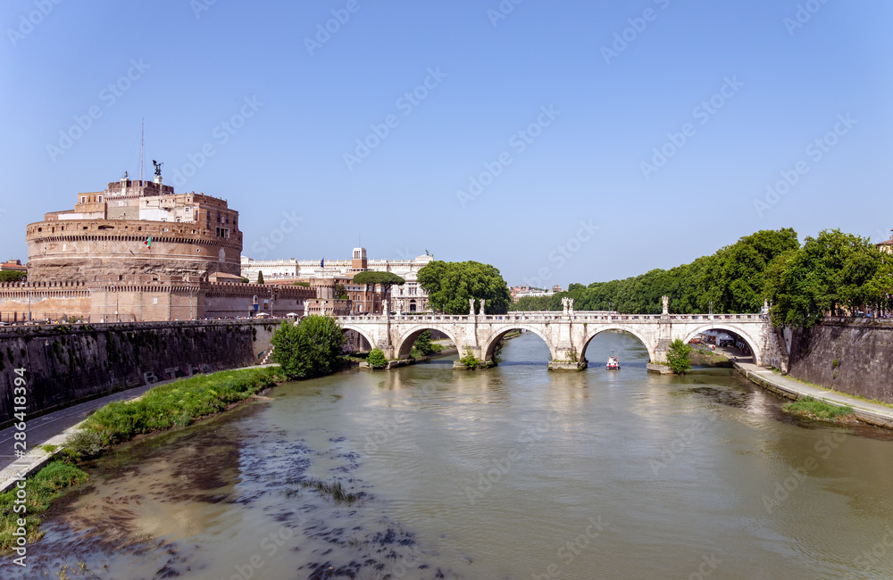 Ponte Sant'Angelo and Castel Sant'Angelo - Rome, Italy. Tourist boat passes under Ponte Sant'Angelo.