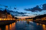 Illuminated Conciergerie and Pont Neuf bridge at night - Paris, France.