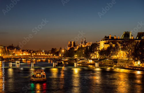 Nightfall over Seine river and illuminated Pont des arts with palais royal and musee d'orsay in background - Paris, France