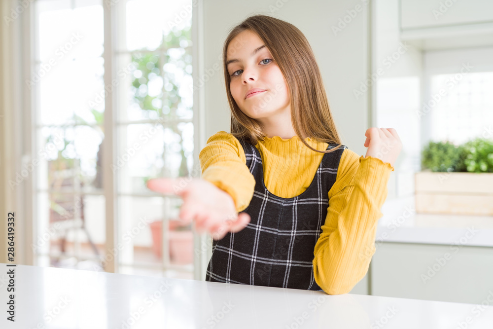 Young beautiful blonde kid girl wearing casual yellow sweater at home smiling cheerful offering palm hand giving assistance and acceptance. Young beautiful blonde kid girl wearing casual yellow sweater at home smiling cheerful offering palm hand giving assistance and acceptance.