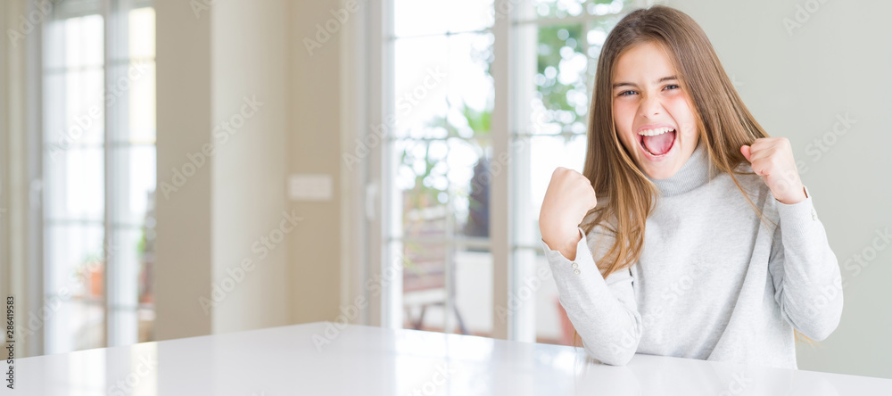 Wide angle picture of beautiful young girl kid wearing casual sweater very happy and excited doing winner gesture with arms raised, smiling and screaming for success. Celebration concept. Wide angle picture of beautiful young girl kid wearing casual sweater very happy and excited doing winner gesture with arms raised, smiling and screaming for success. Celebration concept.