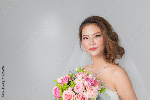Asian bride standing and holding a bouquet..