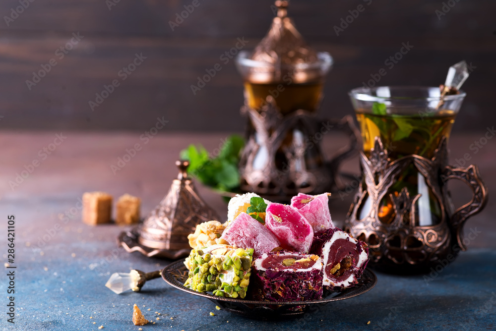 Traditional turkish sweets with tea mint in a traditional glass on a concrete background