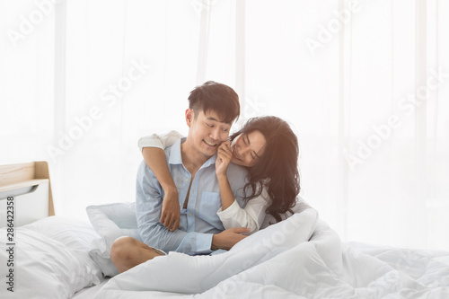 Couple sitting on bed, they hug each other by love..