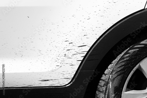 Side view of a very dirty car with bitumen stain. Fragment of a dirty SUV. Dirty headlights, wheel and bumper of the off-road car with swamp splashes on a side panel