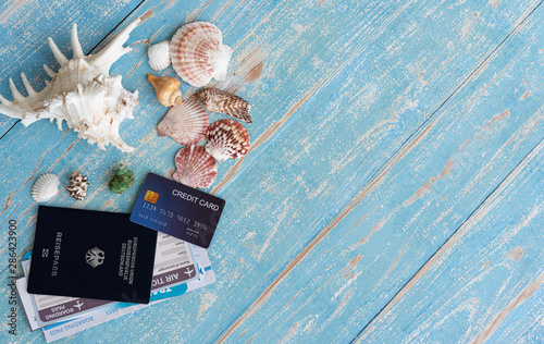 Summer holiday theme background setting with different sea shell, passport and credit card in blue ocean wood, Copy space for text