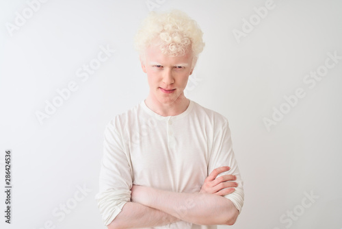 Young albino blond man wearing casual t-shirt standing over isolated white background skeptic and nervous, disapproving expression on face with crossed arms. Negative person. photo