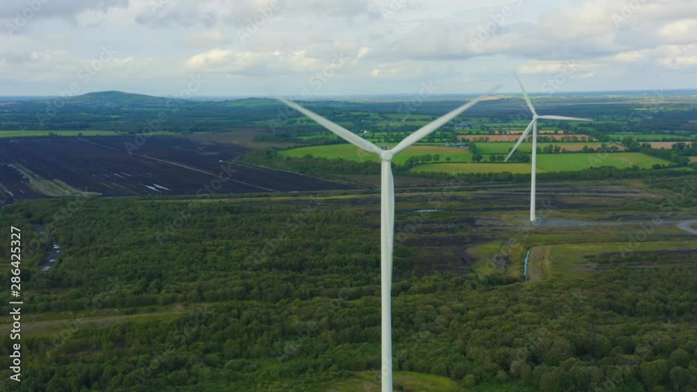 Aerial view of Wind turbines Energy Production- 4k aerial shot on sunset. 4k drone footage turbines. Panning shot with more wind turbines coming into frame. Background is the Irish landscape and bog. Aerial view of Wind turbines Energy Production- 4k aerial shot on sunset. 4k drone footage turbines. Panning shot with more wind turbines coming into frame. Background is the Irish landscape and bog.