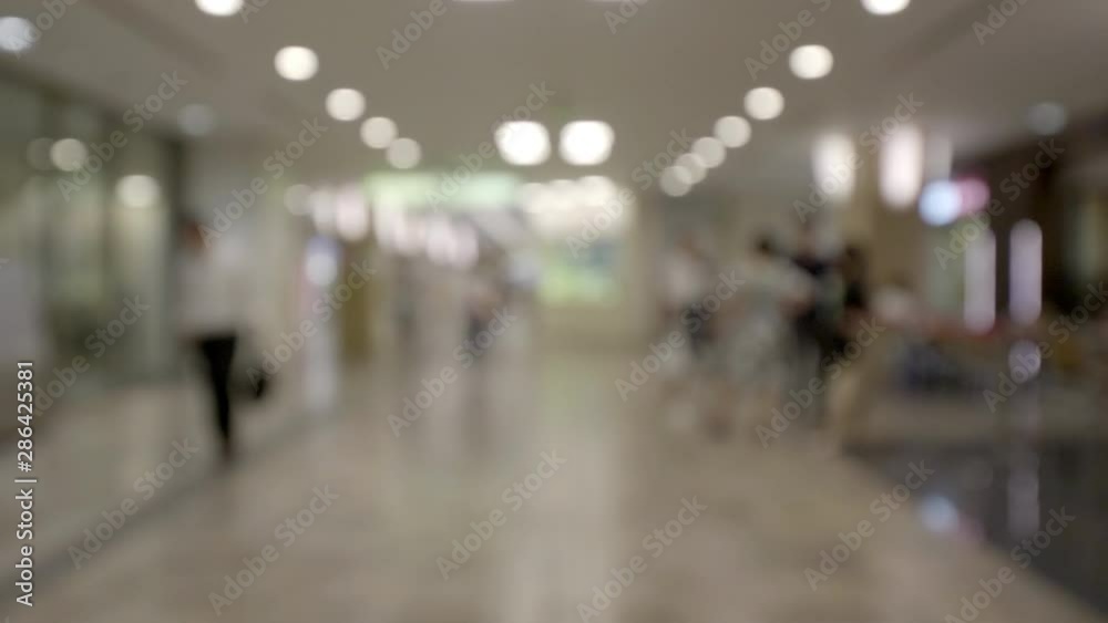 Defocused view of a bright wide hallway in a modern office building. Glass walls of meeting rooms, people walking in the corridor. Intentional blur. Defocused view of a bright wide hallway in a modern office building. Glass walls of meeting rooms, people walking in the corridor. Intentional blur.