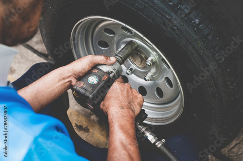 Hands of mechanic changing car wheel in auto repair service with Impact Wrench