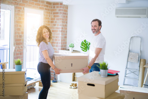 Middle age senior couple moving to a new house, holding cardboard boxing smiling happy in love with apartmant © Krakenimages.com