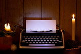 Retro typewriter with a blank sheet of paper for text. Dark Christmas and New Year background. Mock up, Copy space with gifts and a candle.