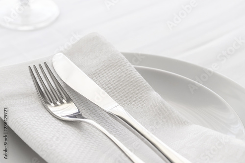 Close up of silverware fork and knife with napkin on the plate.  Restaurant dinning concept.