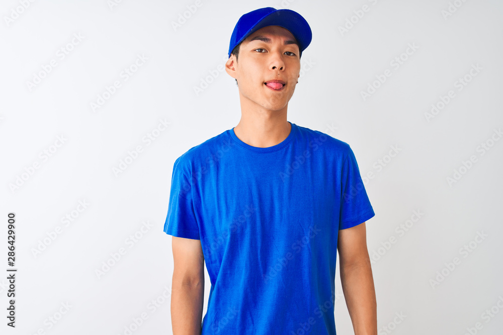 Chinese deliveryman wearing blue t-shirt and cap standing over isolated white background sticking tongue out happy with funny expression. Emotion concept. Chinese deliveryman wearing blue t-shirt and cap standing over isolated white background sticking tongue out happy with funny expression. Emotion concept.