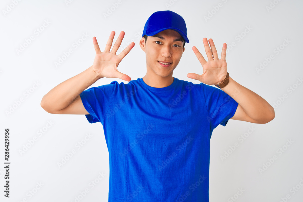 Chinese deliveryman wearing blue t-shirt and cap standing over isolated white background showing and pointing up with fingers number ten while smiling confident and happy. Chinese deliveryman wearing blue t-shirt and cap standing over isolated white background showing and pointing up with fingers number ten while smiling confident and happy.