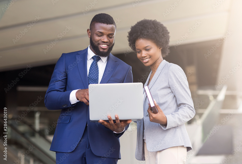Business man and woman using laptop outdoors