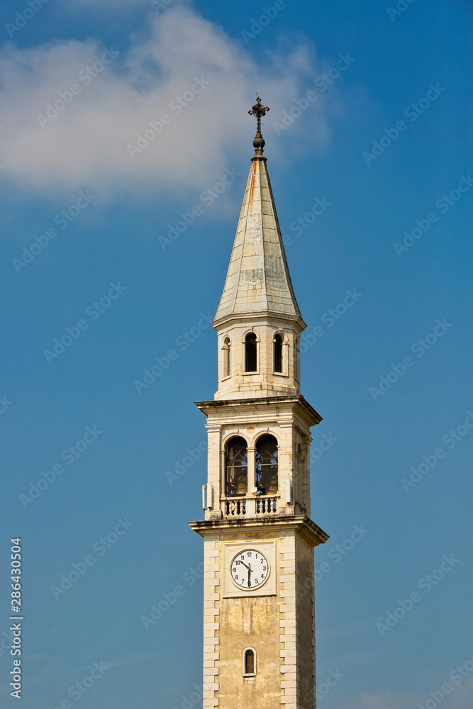 Bell tower of the church in Gallio, Vicenza, Italy against the blue sky with one white cloud